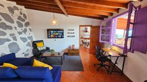 a living room with a blue couch and a stone wall at Los Cerrajones: spectacular views from the cliff in Agulo