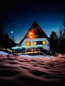 a house with a lit up sign in the snow at Holiday home Bozica in Lokve