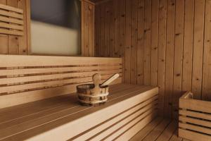 a wooden sauna with a wooden spoon in a bucket at Thalguter - Rooms & Breakfast in Lagundo