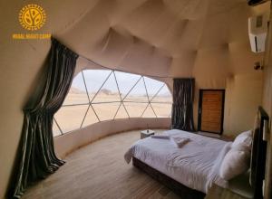 a bedroom with a bed and a large window at Miral Night Camp in Wadi Rum
