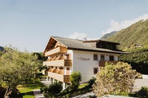 un edificio con árboles y montañas al fondo en Thalguter - Rooms & Breakfast, en Lagundo