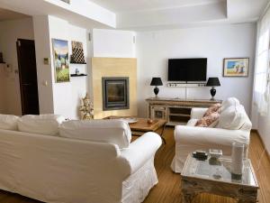 a living room with white furniture and a flat screen tv at Casa Roja in Almuñécar