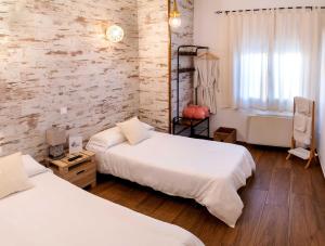 a bedroom with two beds and a brick wall at La Posada de Dulcinea in Mota del Cuervo