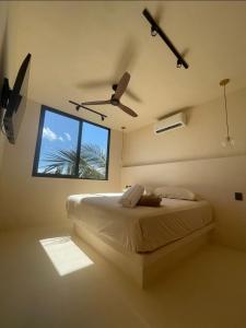 1 dormitorio con 1 cama, ventilador de techo y ventana en Casa Hood By the Sea en Holbox Island