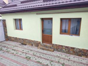 a white house with a wooden door and windows at Torok Adrian Mihail PFA in Râşnov +8 photos