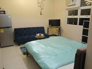 een woonkamer met een blauw bed en een bank bij 101 condo furnished walking distance NIAA 3 in Manilla
