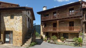 un antiguo edificio de piedra con un balcón en el lateral en Conjunto Rural la Tejedora. Albergue y estudios familiares. en Rasines