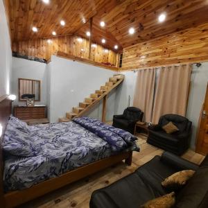 1 dormitorio con cama, sofá y techos de madera en The Kunhar Beach Cottage By Country Club Balakot en Bālākot