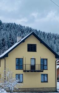 ヤレムチャにあるWeekend houseの雪の中のバルコニー付きの黄色い家
