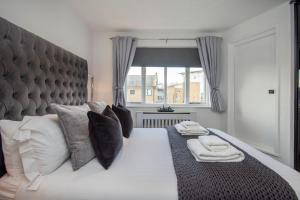 - une chambre avec un grand lit, des oreillers et une fenêtre dans l'établissement 2 Bed town house with Garden in Hackney, London, à Londres