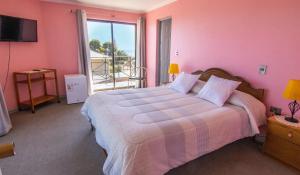 1 dormitorio con 1 cama grande y paredes de color rosa en Hotel Rocas del Pacifico en Pichilemu