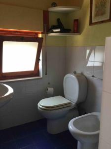 baño con aseo y lavabo y ventana en Stanza panoramica con terrazza privata sul mare, en Marzamemi