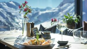 a table with a plate of food and a glass of wine at Ludwig‘s Mountain Lodges in Dalaas