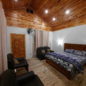 a bedroom with a bed and chairs in a room at The Kunhar Beach Cottage At Country Club Balakot in Bālākot