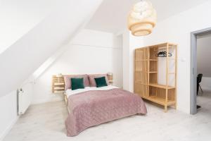Dormitorio blanco con cama y estante de libros en Apartament Starówka by RENT4YOU, en Olsztyn
