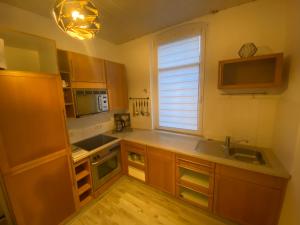 eine Küche mit Holzschränken, einem Fenster und einem Waschbecken in der Unterkunft Gemütliches Apartment mit Kamin in Oldenburg