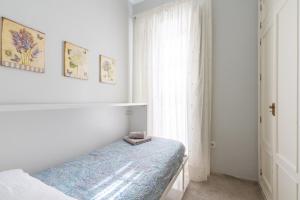 een witte slaapkamer met een bed en een raam bij San Lorenzo en Esencia in Sevilla