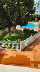 uma cerca branca com flores ao lado de uma piscina em ALAMO LUXURY APARTMENT em Playa del Inglés