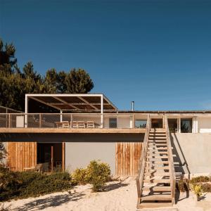 una casa sulla spiaggia con un ponte di legno di Campo de Arroz a Carvalhal