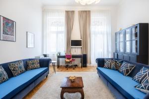 ein Wohnzimmer mit blauen Sofas und einem Tisch in der Unterkunft Court Crossing Apartment in Budapest