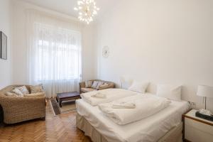 ein weißes Schlafzimmer mit einem großen Bett und einem Stuhl in der Unterkunft Court Crossing Apartment in Budapest