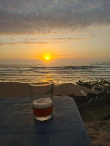 a glass of beer sitting on a table at the beach at Grotte au bord de mer in Tiznit