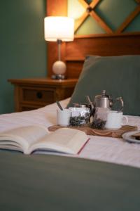 um livro aberto sobre uma cama com um conjunto de chá e chávenas em HOSTAL CRUZ CHICA em La Cumbre