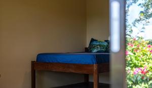Cama en habitación con sábanas azules y ventana en Hush Maderas en San Juan del Sur