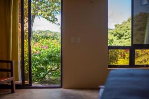 a room with an open door with a view of a garden at Hush Maderas in San Juan del Sur