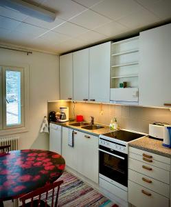 a kitchen with white cabinets and a table and a sink at Chalet Mummola in Naamijoki