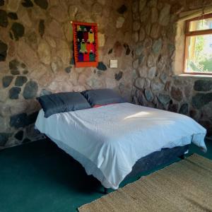 1 dormitorio con 1 cama en una pared de piedra en Refugio de Montaña "Casa Chakana " en Luján de Cuyo
