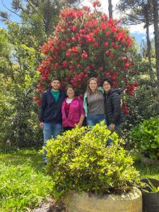 un grupo de personas de pie en frente de un arbusto de flores en Cabanas Brocker, en Gramado