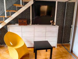 a yellow chair and a dresser with a tv at Apartman Stepa K3 in Belgrade +11 photos