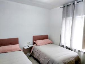 two beds in a small room with a window at La casita de Soria in Soria