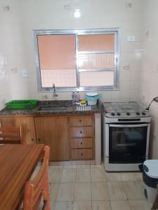 een keuken met een fornuis, een wastafel en een tafel bij Apartamento Perto da Praia in Praia Grande