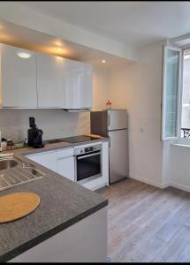 eine Küche mit weißen Schränken und einem Kühlschrank in der Unterkunft Golden Mont Centre Appartement in Pau