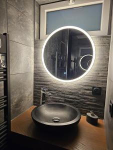 een ronde wastafel in een badkamer met een spiegel bij L'ÉTOILE AZ - vue lac - Sauna privé in Tresserves