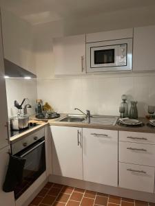 a white kitchen with a sink and a microwave at Appartement Charles Le Brun, Face au Château de Versailles, avec parking privé in Versailles +24 photos