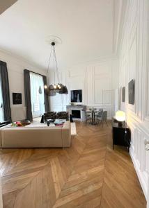 a living room with a white couch and wooden floors at Appartement Charles Le Brun, Face au Château de Versailles, avec parking privé en sous sol in Versailles