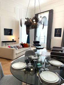 a living room with a glass table and chairs at Appartement Charles Le Brun, Face au Château de Versailles, avec parking privé en sous sol in Versailles