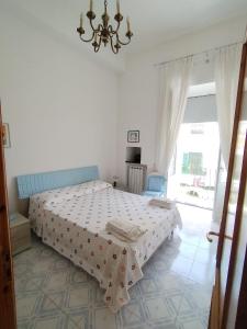 Habitación blanca con cama y lámpara de araña. en Ischia Ponte romantic apartment in the historical center and near the sea, en Isquia