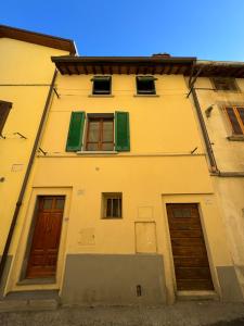 a yellow building with green windows and doors at Il Pentolo in Sansepolcro