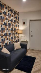 sala de estar con sofá azul y pared geométrica en La piccola Noralù, en Grottaferrata