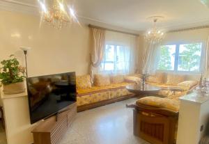 a living room with a couch and a tv at Spacieux et familial à 2 minutes à pied du stade de football de RABAT in Rabat