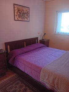 een slaapkamer met een bed met paarse lakens en een raam bij La Chiocciola...The Snail in Bussoleno