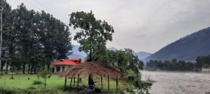 a house with a tree in the middle of a field at Apartment - Country Club Balakot in Bālākot