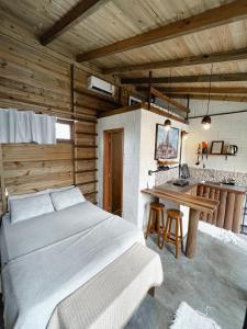 1 dormitorio con 1 cama y cocina con mesa en Recanto do Xamã - Praia do Rosa, en Praia do Rosa