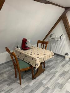 ein Tisch und Stühle mit einem roten Spielzeug darüber in der Unterkunft Chambre rustique avec double lit et sa salle de bain privée in Urbès