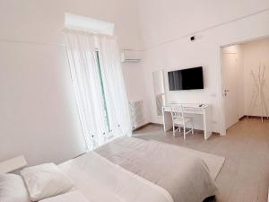 ein weißes Schlafzimmer mit einem Bett und einem Schreibtisch in der Unterkunft Donna Anna in Polignano a Mare