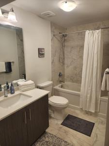 a bathroom with a toilet and a sink and a tub at Cozy, Spacious 2 bdrm basement apartment with kitchenette, sleeps up to 5 in Brampton